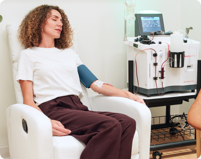 Curly-haired patient seated in a clinic chair during a Complete Blood Cleanse session