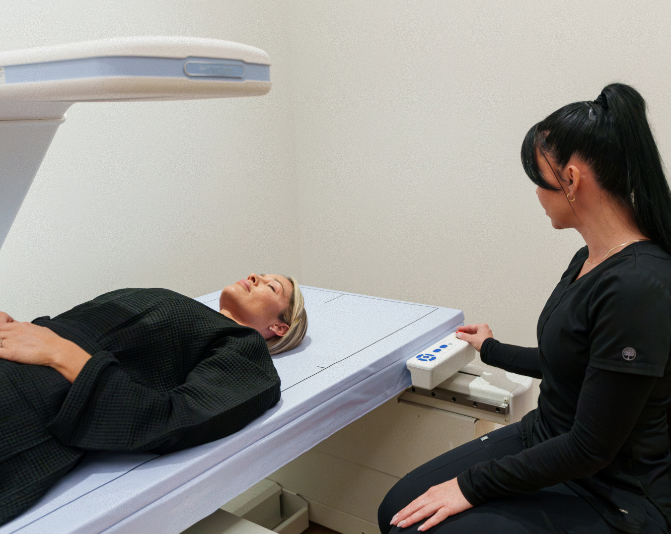 Patient on a DEXA scan table with a technician operating the imaging arm
