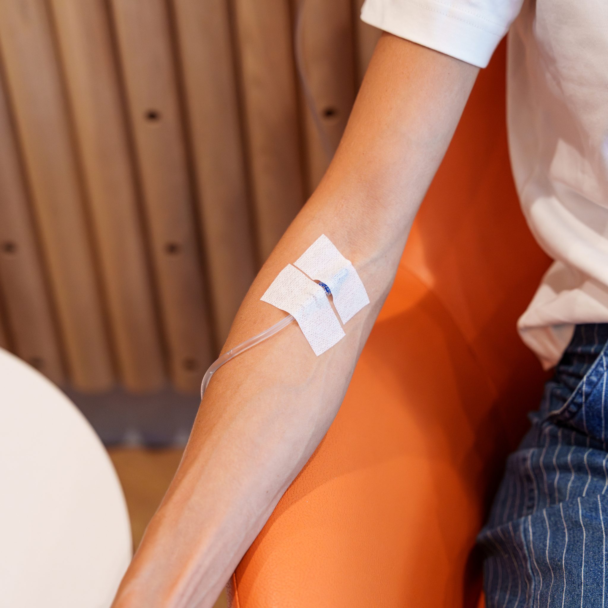 Close-up of an IV line taped to a patient's forearm in clinic