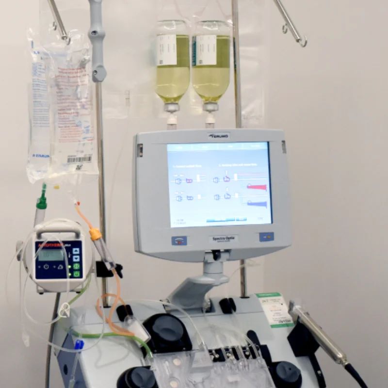 Apheresis machine with a touchscreen monitor and hanging plasma and saline bags in a clinic